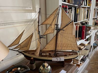 a model of a sailboat on a table in front of a bookshelf