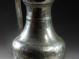 un vase en argent posé sur une table, sur fond noir