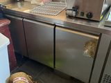 stainless steel counter top in a commercial kitchen with a bag of bread on the floor