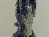 une statue bleue et blanche représentant un homme tenant un sac