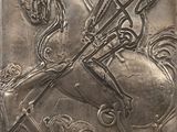 une plaque métallique sur laquelle figurent un cheval et son cavalier
