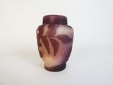 un vase violet posé sur une surface blanche
