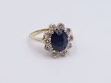 a close up of a blue sapphire and diamond ring on a white surface
