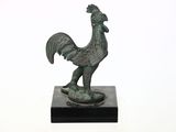statue d'un coq sur un socle noir, sur fond blanc