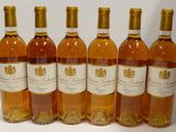 six bouteilles de vin sont alignées sur une surface blanche