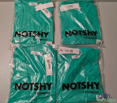 Quatre sacs de t-shirts « notshy » sont posés sur une table
