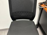 a black office chair sitting in front of a computer desk