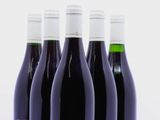 quatre bouteilles de vin rouge sont alignées sur une surface blanche