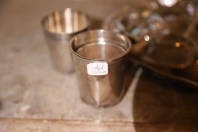 une tasse en argent posée sur une table, à côté d'un plateau sur lequel se trouvent d'autres tasses en argent