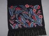 a close up of a black scarf with flowers and leaves on it