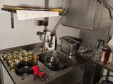 une cuisine équipée d'un évier, d'une cuisinière et d'autres objets posés sur le plan de travail