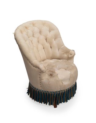 une chaise rembourrée avec des franges sur les pieds
