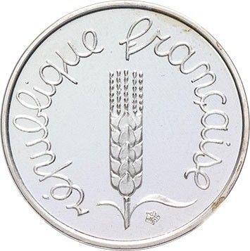 a close up of a silver coin with a plant on it