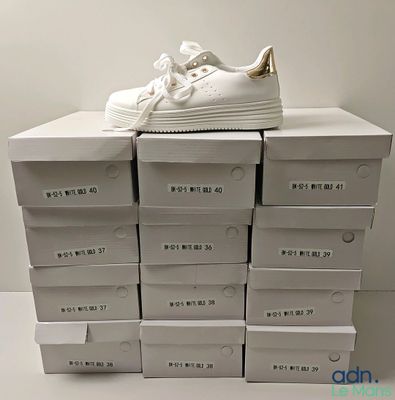 une pile de cartons sur laquelle est posée une paire de chaussures blanches