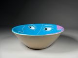 blue and white bowl with a face painted on the side of it