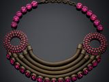 a pink and gold necklace with pink stones on a black background