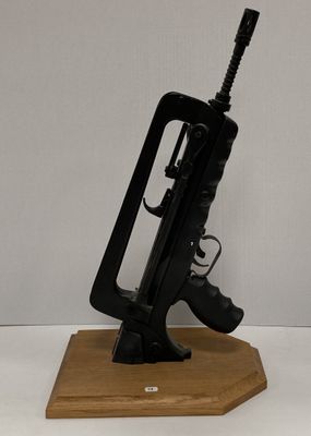 un petit pistolet jouet posé sur un socle en bois, lui-même posé sur une surface blanche