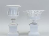 pair of white vases with handles on pedestals against a gray background