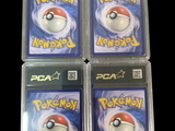 three packs of pokemon cards are in plastic cases on a black surface