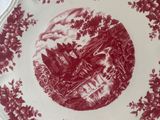 a red and white plate with a picture of a castle on it