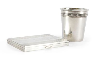 une coupe en argent posée à côté d'un coffret en argent sur une surface blanche