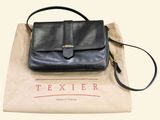 black leather handbag sitting on top of a brown paper bag