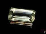 un gros plan d'une tourmaline verte posée sur une surface noire