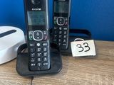 two phones that are sitting on a table next to a charger