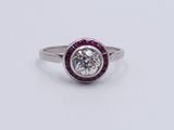 a close up of a diamond and ruby ring on a white surface
