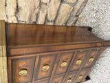 a wooden dresser with many drawers and gold knobs