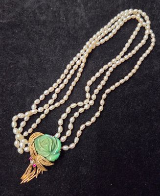 un long collier de perles orné d'une fleur verte et d'un pompon