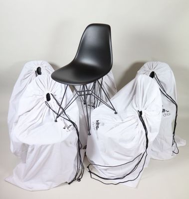 three chairs covered with white covers and a black chair