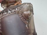 a person holding a silver vase with a lion head on it