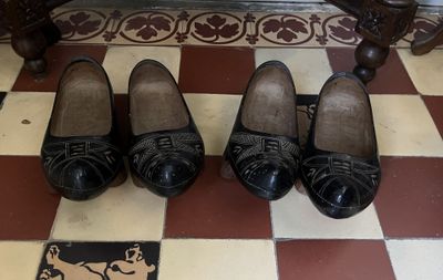 Plusieurs paires de chaussures noires sont alignées sur un sol à carreaux.