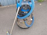 un aspirateur bleu posé par terre à côté d'un mur bleu