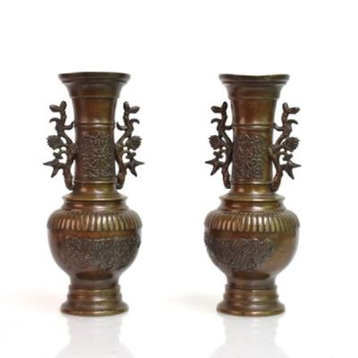 deux vases en bronze posés côte à côte sur une surface blanche