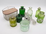 de nombreuses bouteilles et récipients en verre de différentes couleurs posés sur une surface blanche