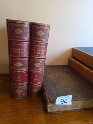 two old books are sitting on a table next to a book case