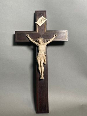 une croix en bois surmontée d'un crucifix, sur fond gris