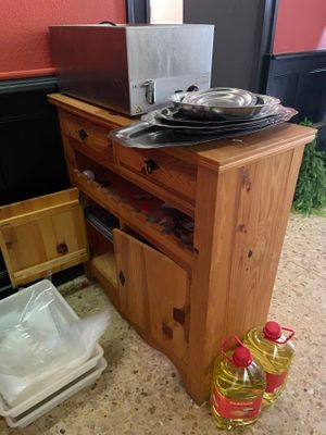 un micro-ondes posé sur un meuble en bois, à côté d'une poubelle