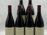 six bouteilles de vin rouge sont alignées sur une surface blanche