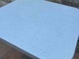 a white table with a blue top sitting on a tile floor