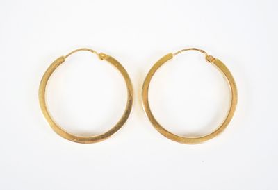 two pairs of gold hoop earrings on a white surface