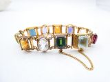 an image of a gold bracelet with multi colored stones on it