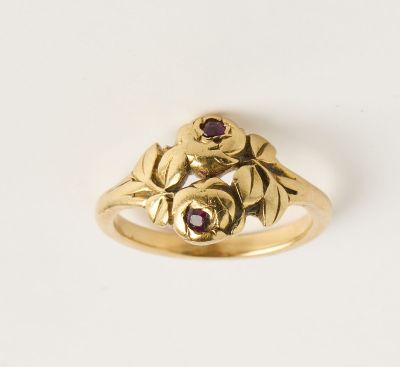 un gros plan d'une bague en or ornée d'une fleur et de feuilles
