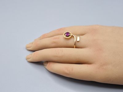 yellow gold ring with a ruby stone on the finger