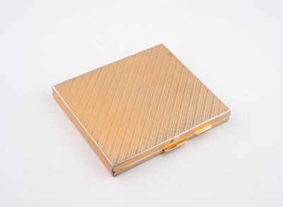 un gros plan d'un étui à cigarettes doré posé sur une surface blanche
