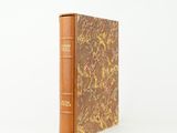 Un vieux livre orné d'un ruban rouge repose sur une surface blanche.