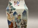a vase with a painting on it sitting on a table
