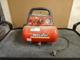 an orange air compressor sitting on top of a table next to a wall